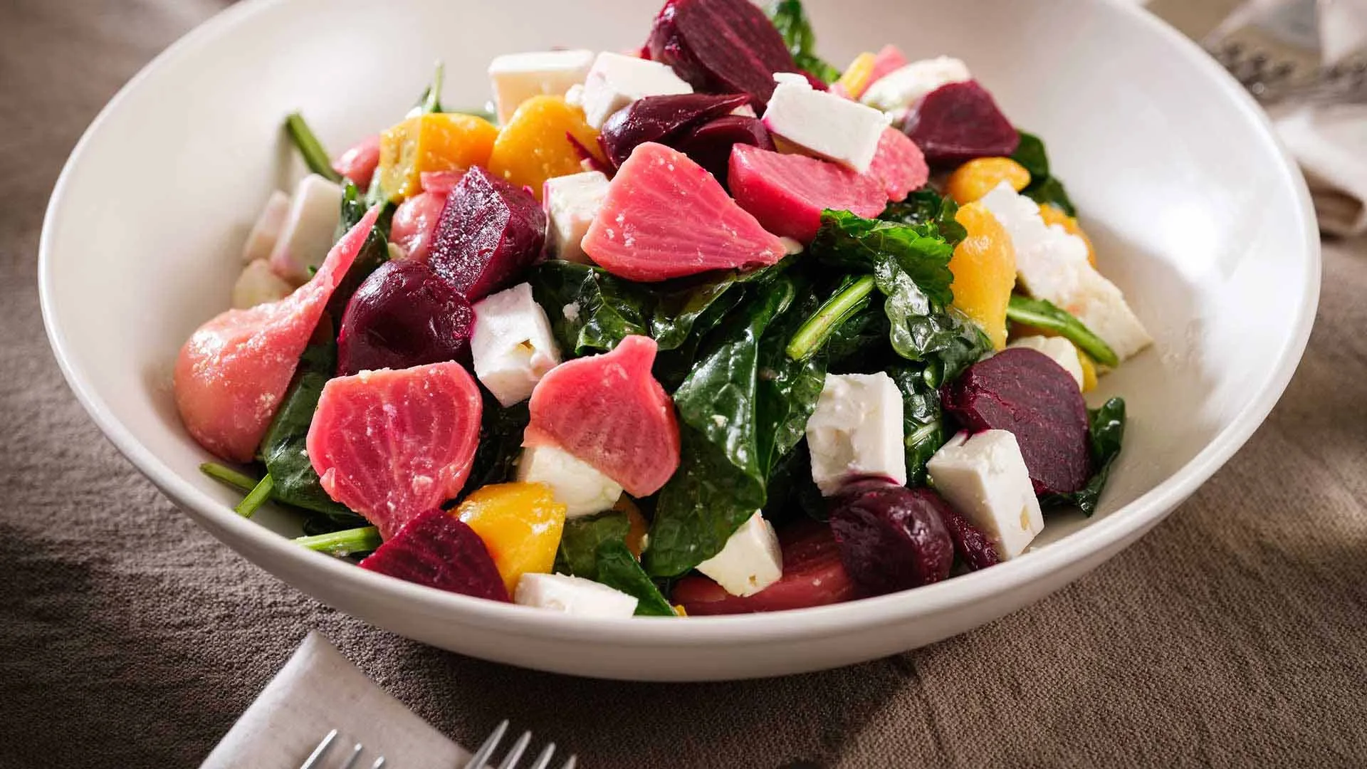 Beet salad and greens in white bowl